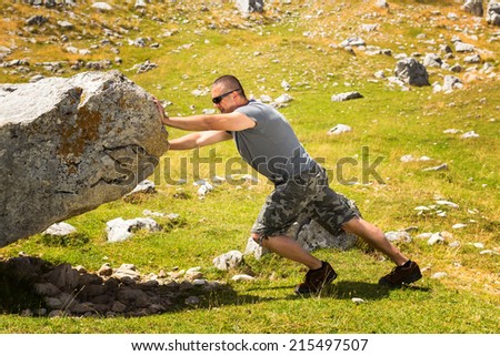 Hard work,the person rolls the rock on mountain