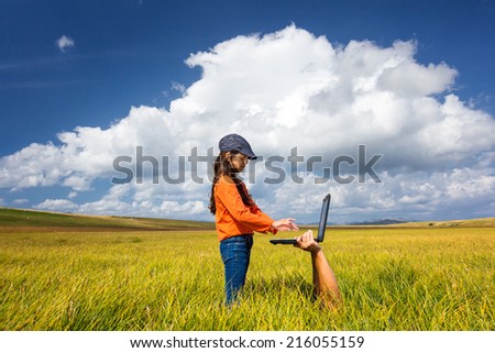 Male hands holding a laptop on the meadow and little girl  type on the keyboard.