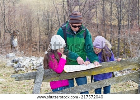 Family hiking in countryside looking for directions on the map.