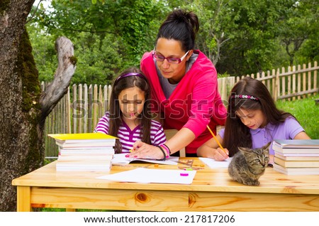 Two beautiful young happy students learn outdoors with teacher.Two beautiful young happy students learn outdoors with mother.