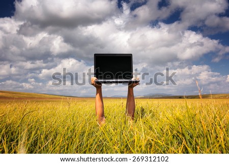 male hands holding a laptop on the meadow