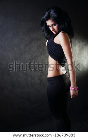 brunette lifted her shirt and shows belly on a black background