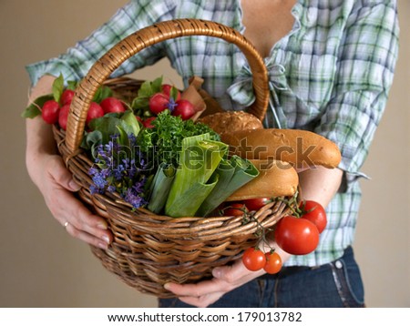 Different fresh vegetables in basket in girls arms with selective focus
