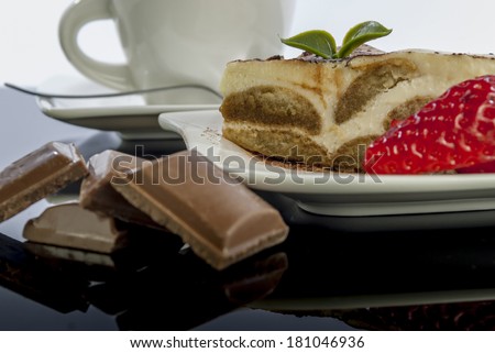 italian desert tiramisu with coffe and strawberry on black reflex background