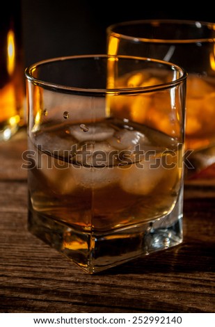 Whiskey, bourbon or brown rum with ice on wood table