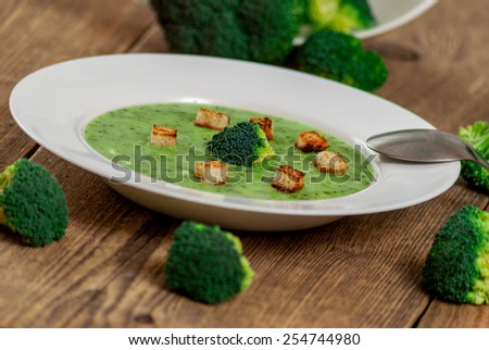 Broccoli soup with croutons in white plate on wood table