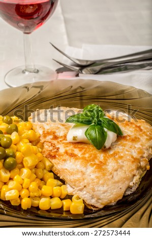 Chicken steak with corn and pea on white table
