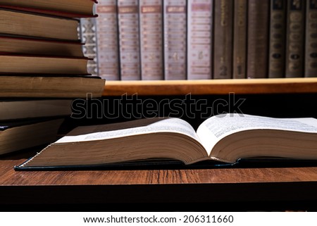 book on the table, the left stack of books against the background of the bookcase