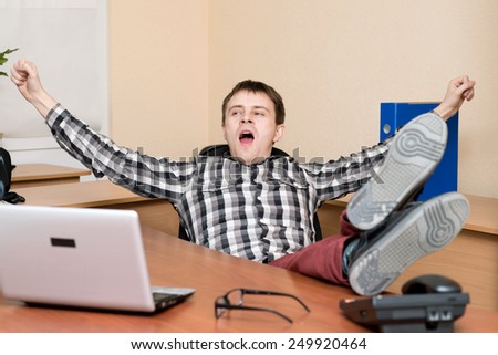Office worker. Young office worker yawning at his desk