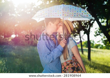 Young couple kissing under an umbrella