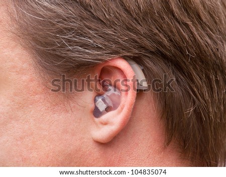 Close-up of a man ear with a high-tech digital behind-the-ear-hearing device