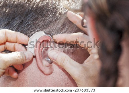 Woman helping to insert a hearing aid
