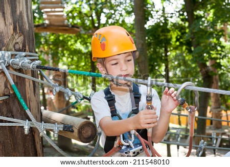 Cute boy with climbing equipment in an adventure park
