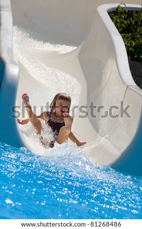 Small girl sliding down a water slide.