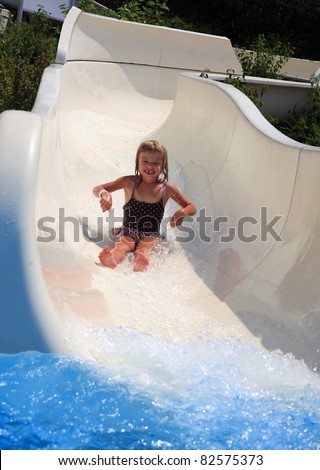 Small girl sliding down a white water slide.