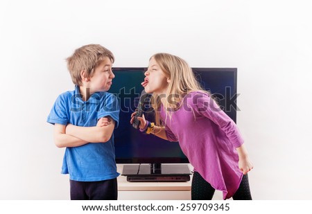 Siblings quarreling over the remote control in front of the television