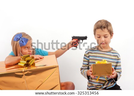Brother and his jealous sister - the small brother is more happy with a smaller gift box than his sister with a big one and she targeting a toy gun at her brother to kill him symbolically