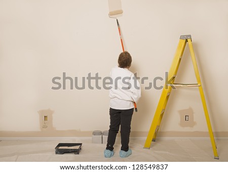Woman Painting A Wall With Room For Copy Space To The Left