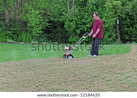 Lawn care showing a Man de-thatching his lawn