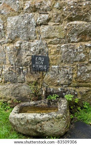 A French sign above an old basin and tap