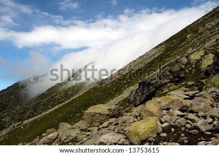 Dense white clouds running from small mountain circus and flow over the ridge