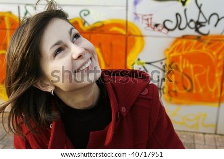 Portrait of a young happy girl in red coat on graffiti background