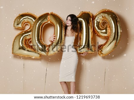 New Year. Woman With Balloons Celebrating At Party. Portrait Of Beautiful Smiling Girl In Shiny Golden Dress Throwing Confetti, Having Fun With Gold 2019 Balloons On Background. High Resolution.