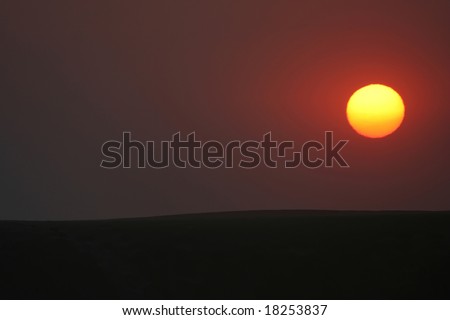Burning sun setting over sand dune