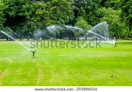 sprinklers spraying water on green grass of a golf course