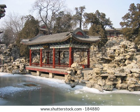 A small chinese building with a frozen lake in front.
