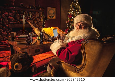 Santa Claus swiping a smart phone with his thumb while smiling at camera