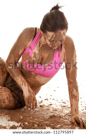 A woman sitting in a bunch of mud, with mud all over her body.