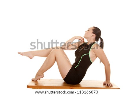 A woman sitting on the bench in her workout clothes with one leg up in the air.