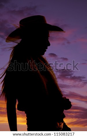 A silhouette of a cowgirl with a beautiful sunset behind her.