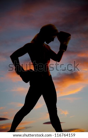 A woman is silhouetted in the colorful sky with boxing gloves.
