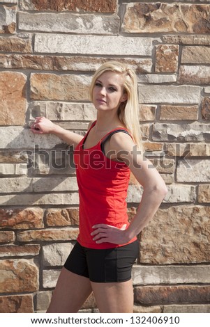 a woman in her fitness clothes standing up by a brick wall