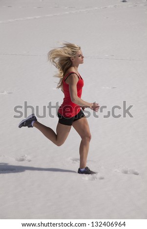 A woman running in her shorts and tank in the snow.