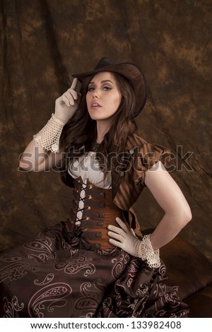 A woman in her vintage western wear with her finger on the brim of her hat.