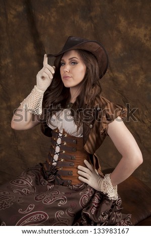 A woman in her vintage western wear with her finger on the brim of her hat.