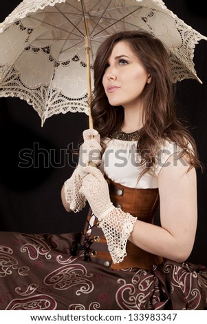A woman looking up in her vintage western dress while holding on to her umbrella.