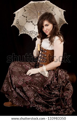 A woman with a small smile on her face holding on to her umbrella in a vintage western dress