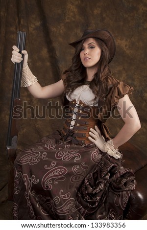 A woman in her beautiful western dress and corset holding on to her shot gun being a real cowgirl.