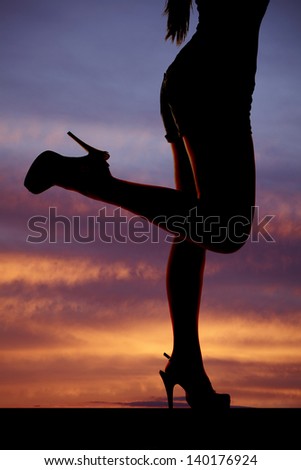 a silhouette of a woman's legs on is kicked back.
