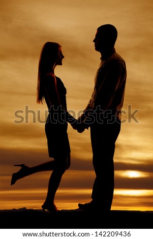 a silhouette of a man and woman holding hands and her leg is up