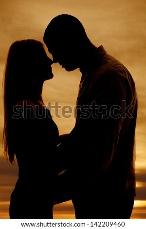 A silhouette of a man and woman with noses touching.