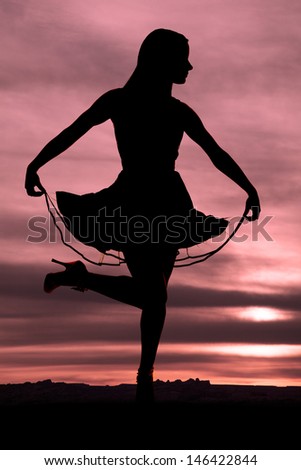 A silhouette of a woman holding up her dress with her foot up