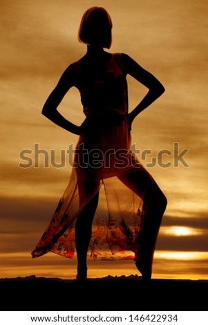 A silhouette of a woman in her lace skirt with her hands on her hips