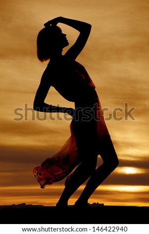 A silhouette of a woman in her flowing dress leaning back