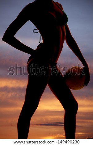 A womans body silhouette in the sunset with a volleyball