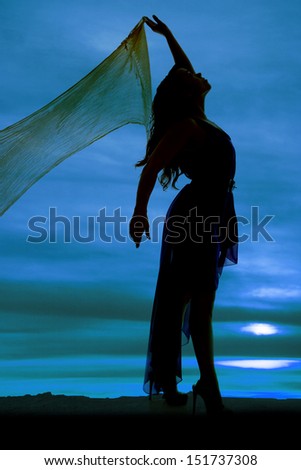 a silhouette of a  woman with her sarong holding it up and dancing.